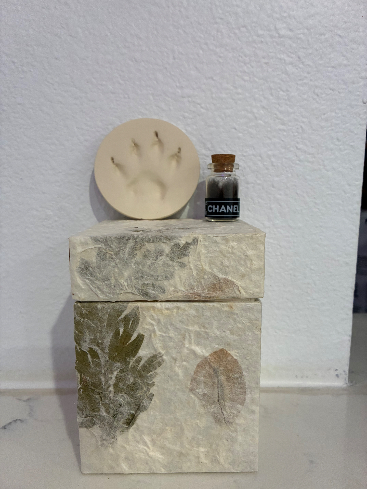 Botanical paper urn with clay paw print and Chanel fur keepsake bottle